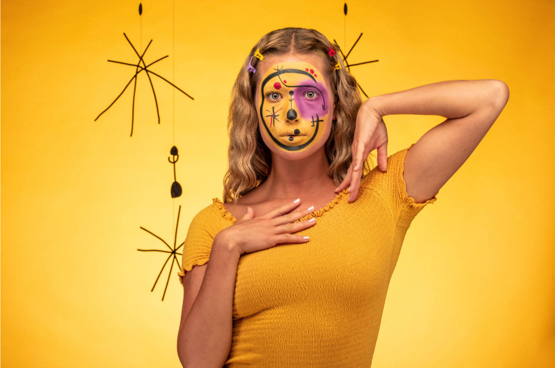 Fotografía plano medio de una joven con maquillaje de rostro inspirado en las pinturas de Miró.