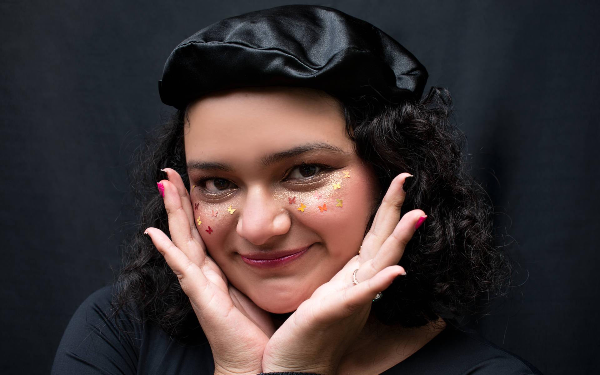 Fotografía close-up de una joven con maquillaje otoñal, sosteniendo su rostro con sus manos.