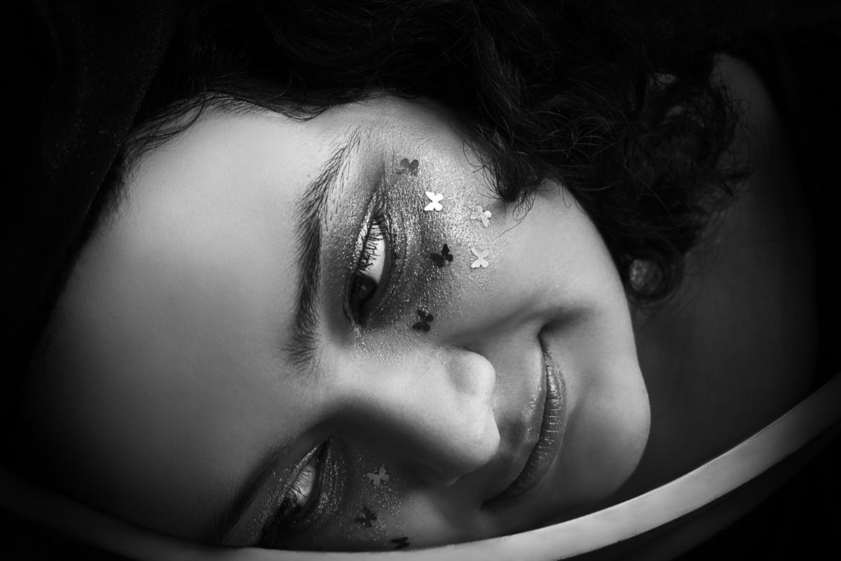 Fotografía close-up en blanco y negro del rostro de una joven con expresión sombría.